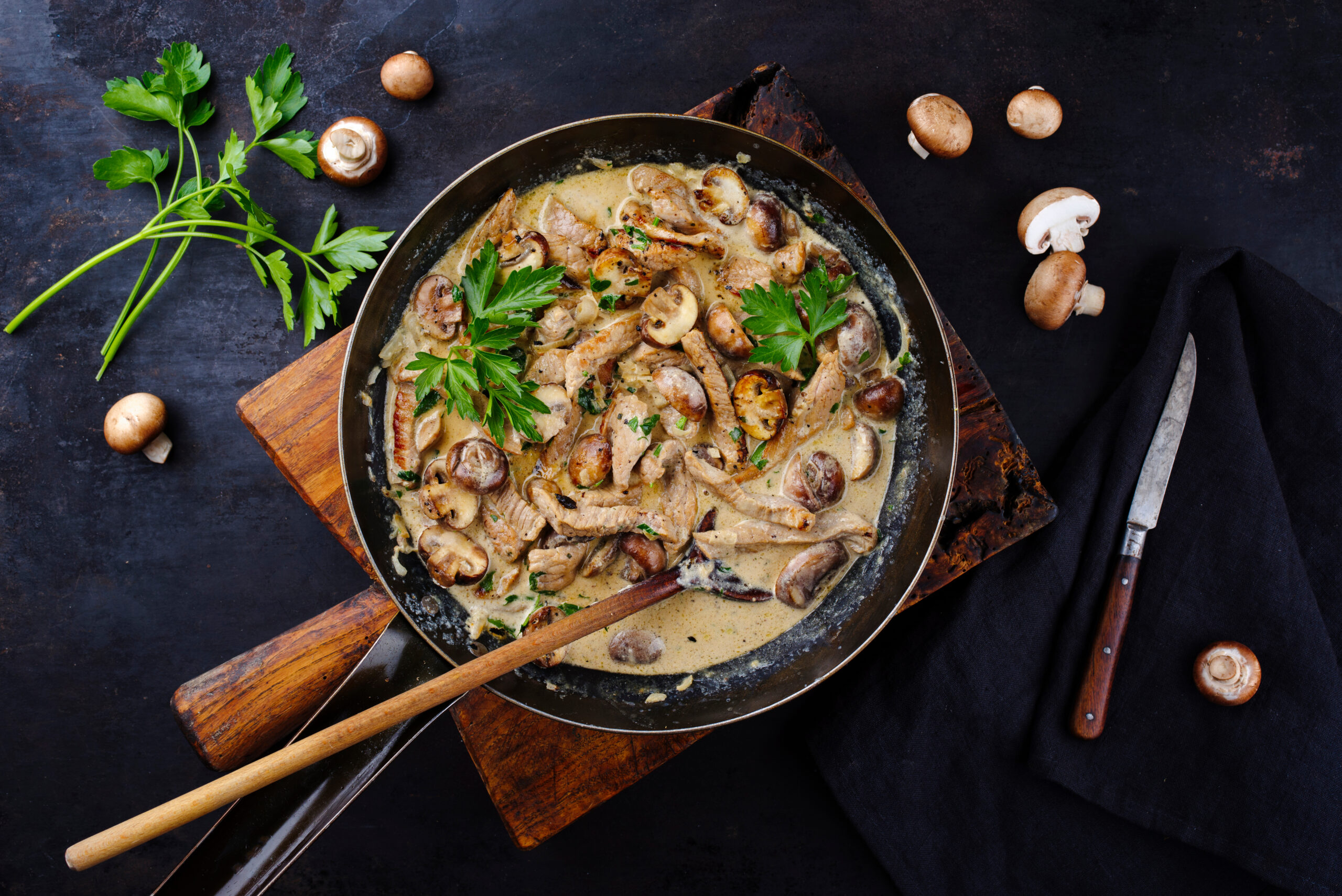 Traditional Swiss Zürcher geschnetzeltes from veal with mushrooms in cream sauce served as top view in a wrought-iron pan